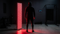 Full-body red light therapy panel glowing in a home gym